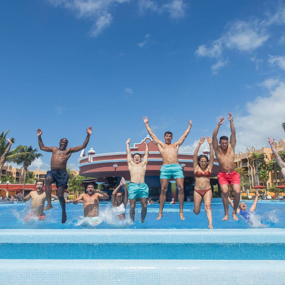 Group of friends jumping into pool at The Royal Haciendas.