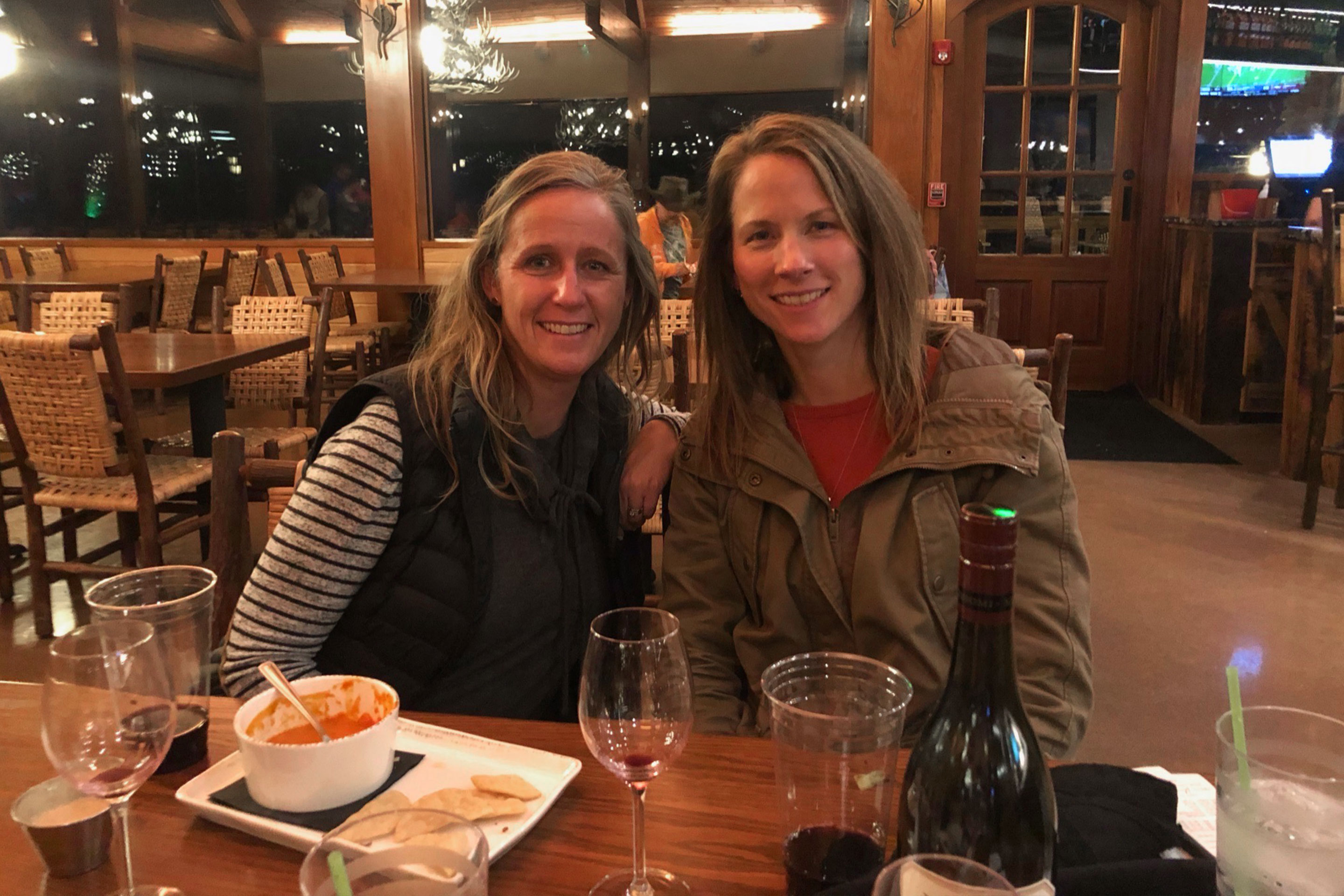 Featured Contributor, Jennifer C. Harmon's two girlfriends wear seated at a table wearing a striped shirt and utility jacket.