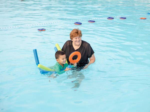 Woman helping child float on pool tubes in outdoor pool at Holiday Hills Resort in Branson, Missouri.