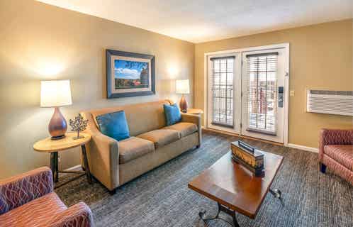 Living room with a sofa, two chairs, and tables in a one bedroom villa at Oak n' Spruce Resort in South Lee, Massachusetts