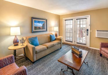 Living room with a sofa, two chairs, and tables in a one bedroom villa at Oak n' Spruce Resort in South Lee, Massachusetts