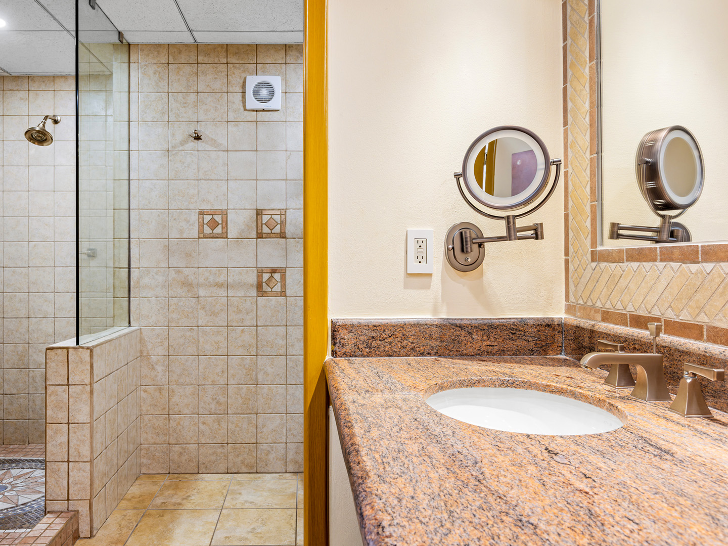 Suite bathroom with a vanity, makeup mirror, and walk-in shower.
