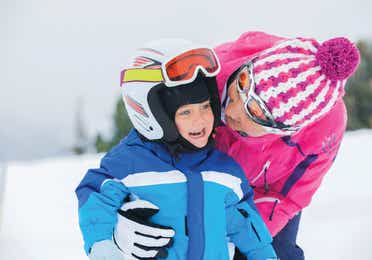 Young child and adult skiing on a snowy mountain