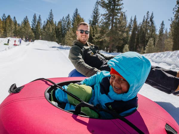 Father and child snow tubing down mountain near Tahoe Ridge Resort in Stateline, Nevada.