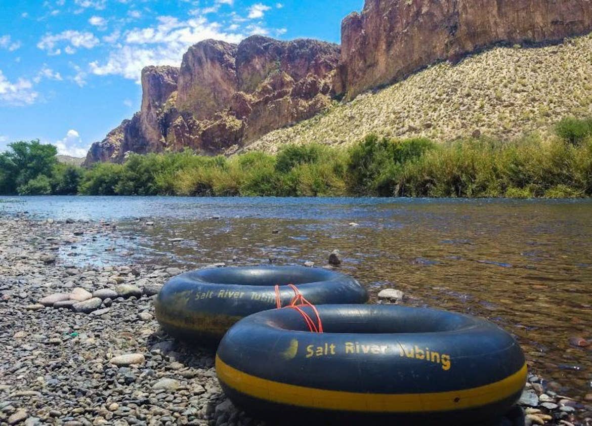 Salt River Tubing floats sitting along the bank of the Salt River with mountain ridges in the distance.