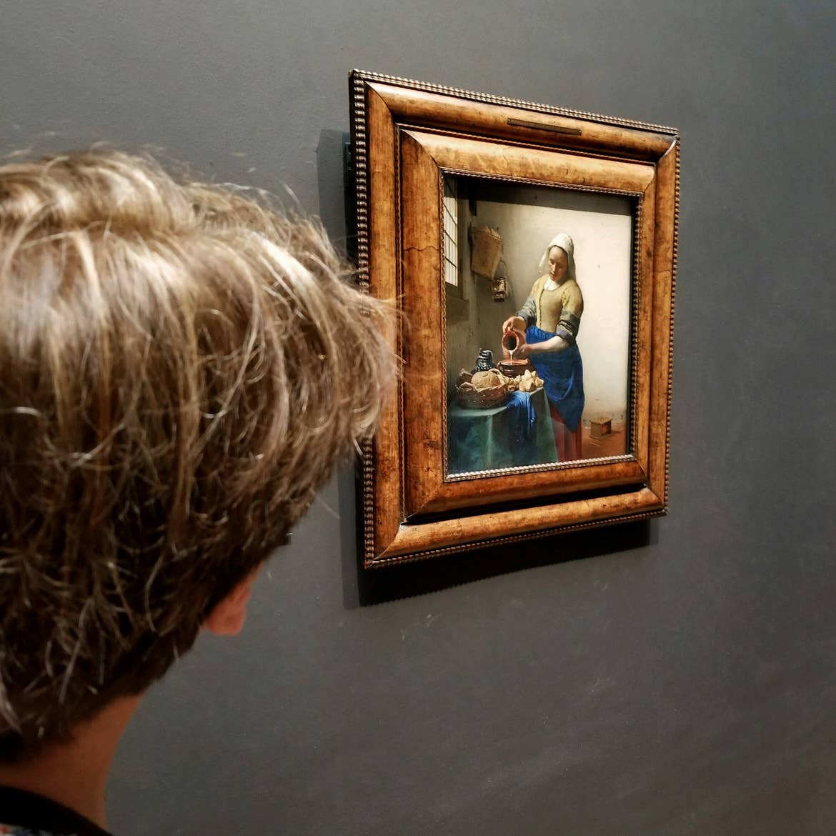 A woman looks at the famous 'The Milkmaid' painting by Johannes Vermeer located at the Rijksmuseum in Amsterdam, Netherlands.