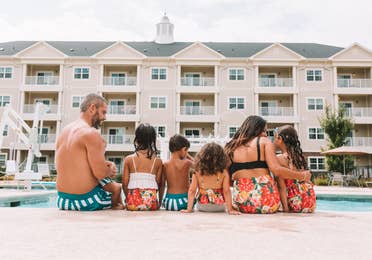 Mother, father, and five children sitting at the edge of a pool at Holiday Inn Club Vacations Williamsburg Resort in Virginia.