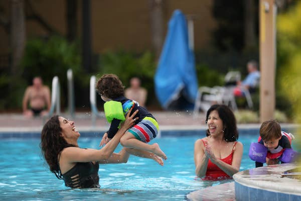 Mother catching her child as he jumps into the pool.