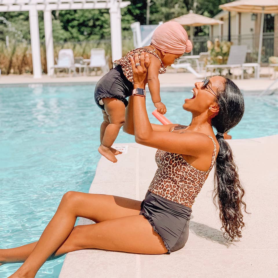 Aesky holding her baby in the air near the pool
