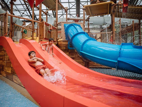 Two kids going down a red and blue waterslide at Pirate's Cay waterpark at Fox River Resort in Sheridan, Illinois.
