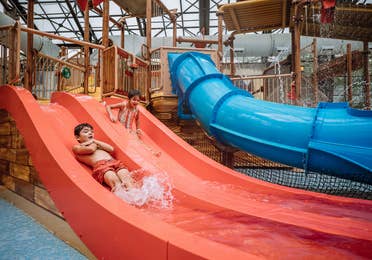 Two kids going down a red and blue waterslide at Pirate's Cay waterpark at Fox River Resort in Sheridan, Illinois.