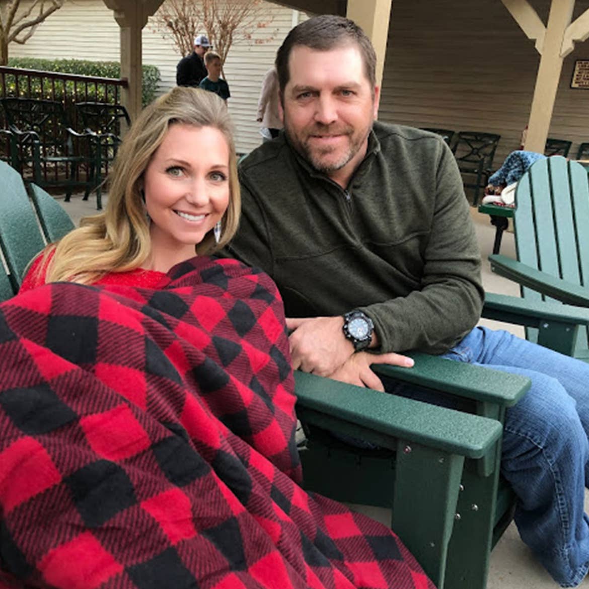 Author, Amanda Nall (left) sits under a cozy festive throw blanket with her husband outdoors.