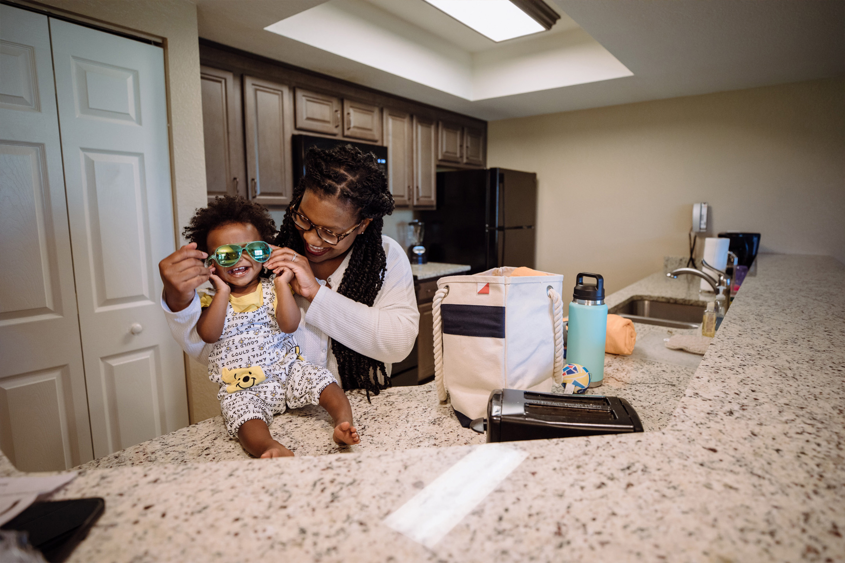 Krystin Godfrey (right) helps her daughter, Creed (left), put on a pair of blue sunglasses on the countertop of their three-bedroom villa in North Village at our Orange Lake Resort located in Orlando, FL.