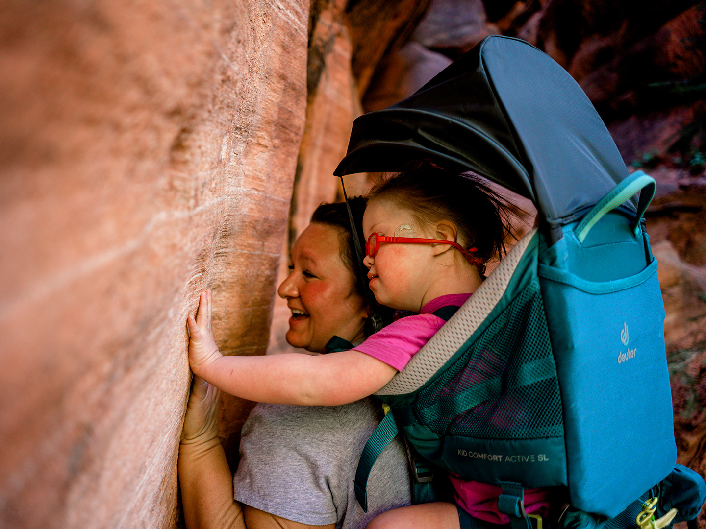 Featured Contributor, Melody Forsyth (left), backpacks with her daughter, Ruby (right), as they touch some rock formations.