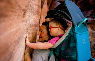Featured Contributor, Melody Forsyth (left), backpacks with her daughter, Ruby (right), as they touch some rock formations.