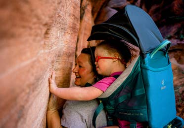 Featured Contributor, Melody Forsyth (left), backpacks with her daughter, Ruby (right), as they touch some rock formations.