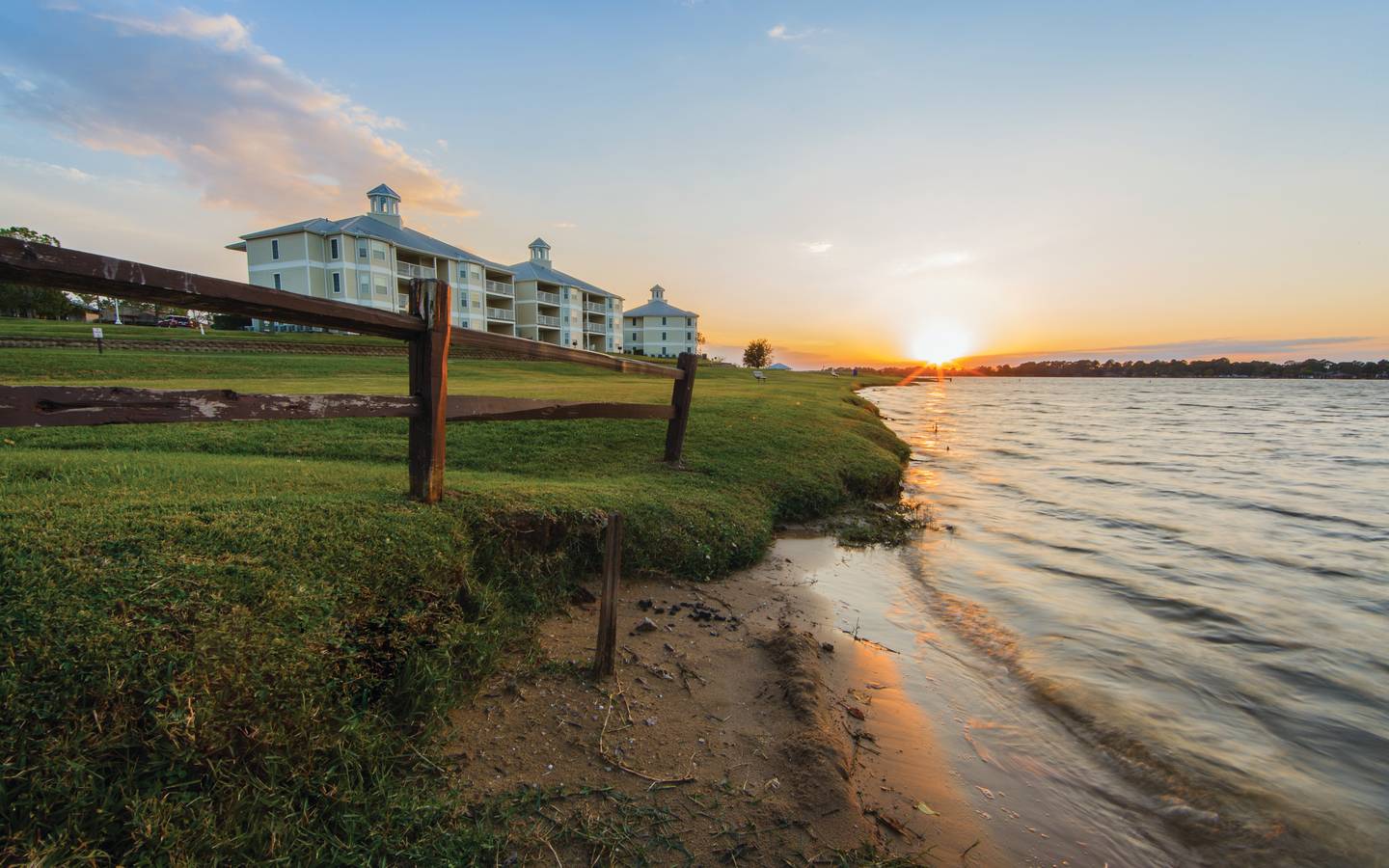 View of property buildings near water at Piney Shores Resort in Conroe, Texas.