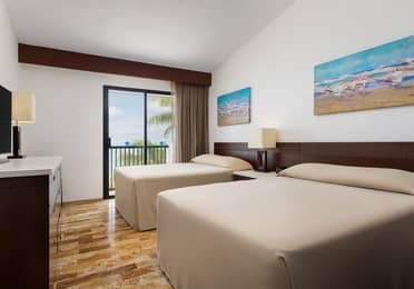 Oceanview villa bedroom with two beds and balcony access.