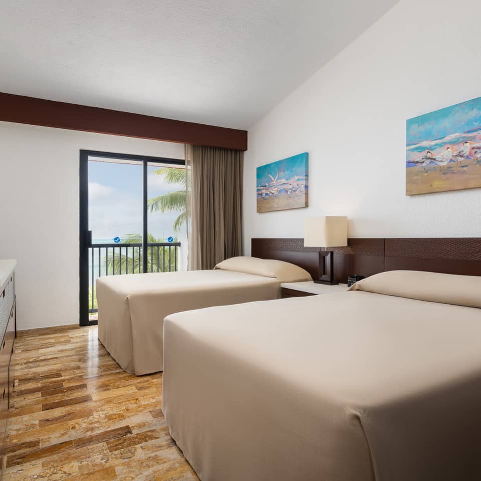 Oceanview villa bedroom with two beds and balcony access.