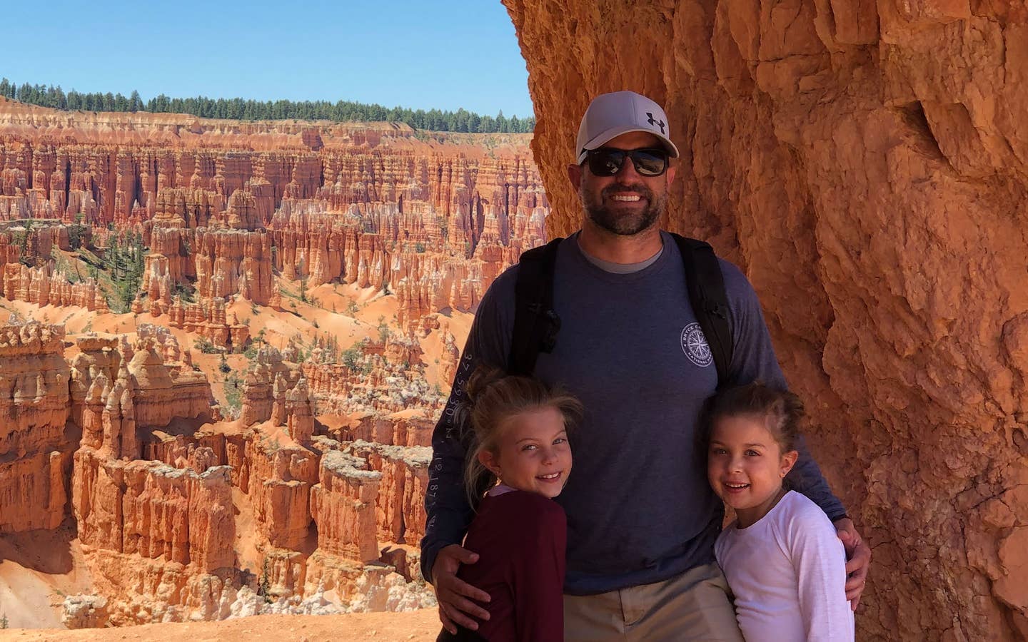 Josh (middle), Kyler (right) and Kyndall (left) stand under an arch formation in front of a gorge.