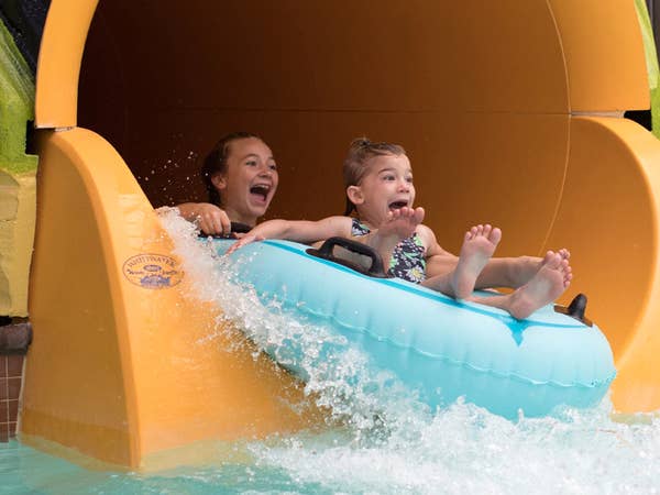 Two children going down waterslide in waterpark.