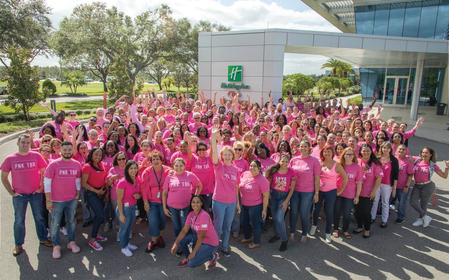 People dressed in pink and smiling for a picture for Pinktoberfest outside of the Holiday Inn Club Vacations' corporate headquarters in Orlando, FL