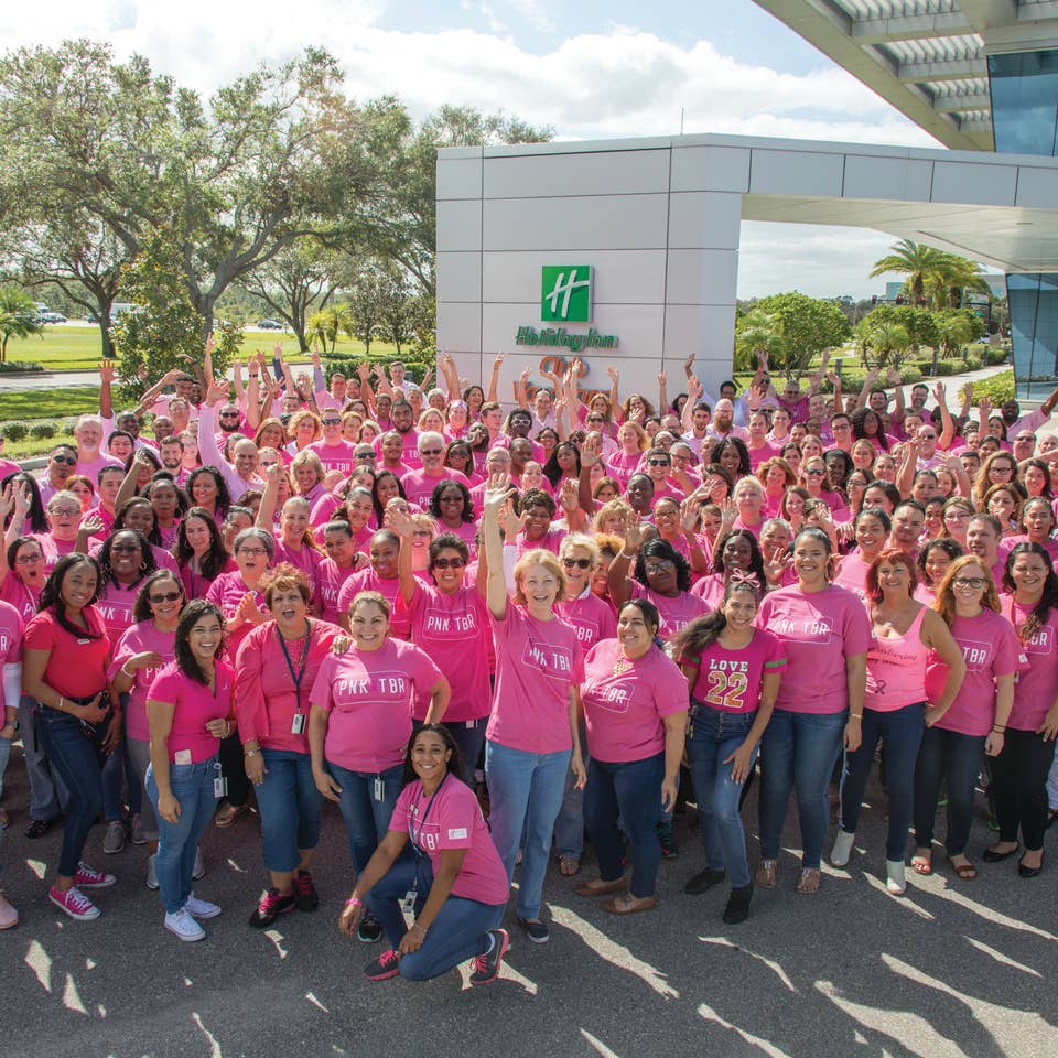 People dressed in pink and smiling for a picture for Pinktoberfest outside of the Holiday Inn Club Vacations' corporate headquarters in Orlando, FL
