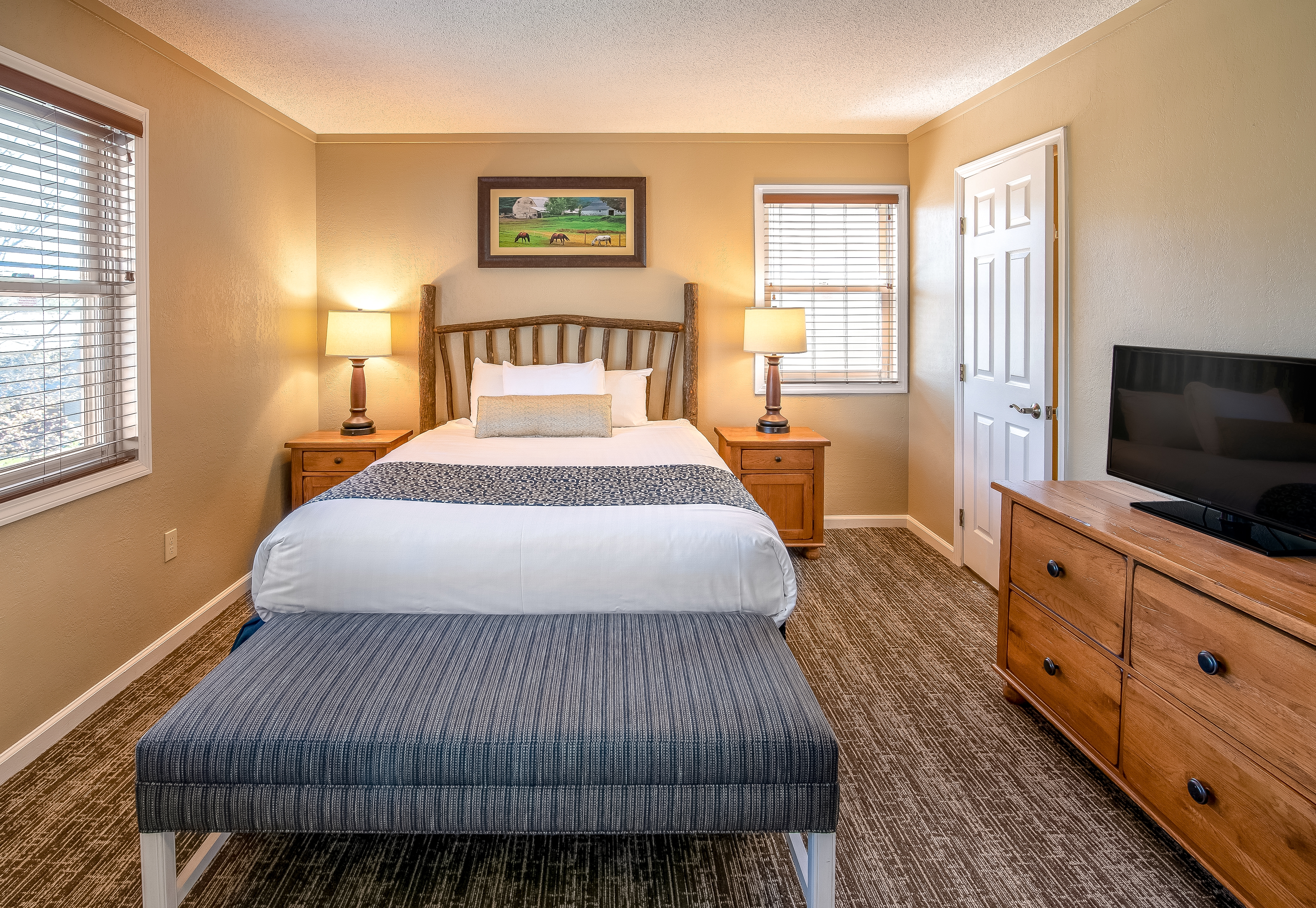 Bedroom with tv, dresser, and end tables in a one bedroom villa at Oak n' Spruce Resort in South Lee, Massachusetts