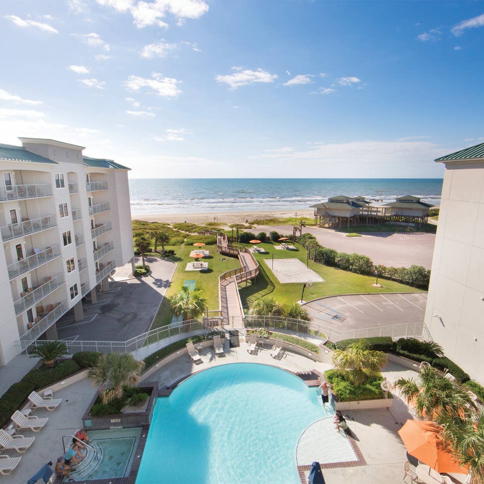 View of outdoor infinity pool and beach from Galveston Beach Resort room balcony in Texas.