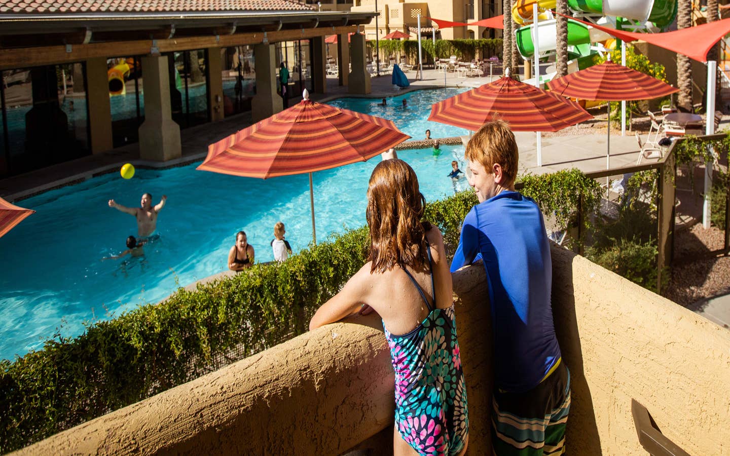 Two kids looking at pool and waterslide from balcony at Scottsdale Resort in Arizona.