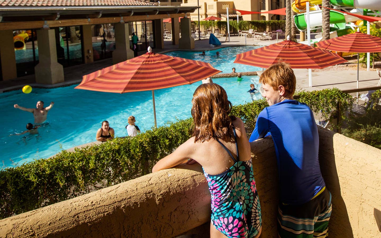 Two kids looking at pool and waterslide from balcony at Scottsdale Resort in Arizona.