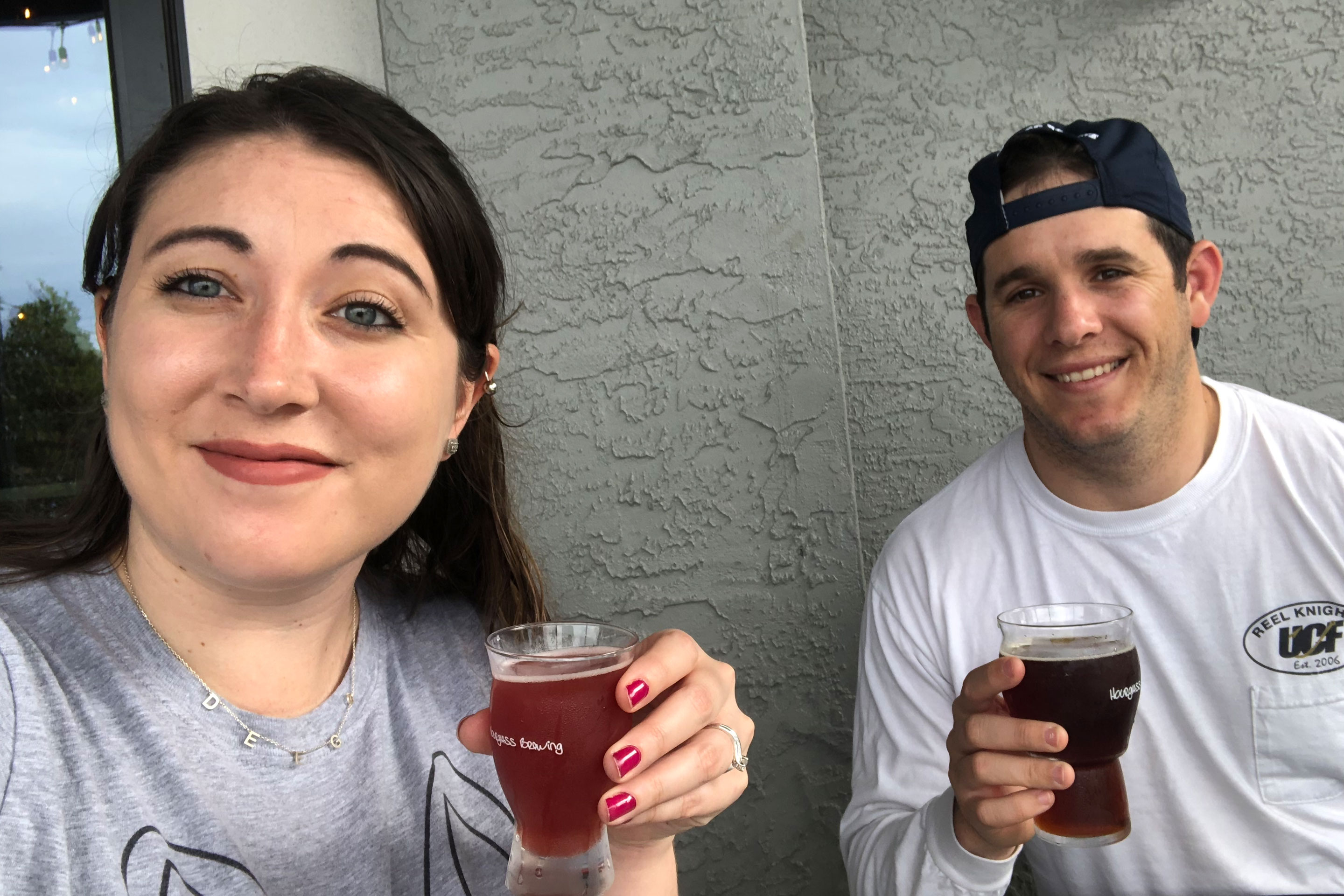 Featured Contributor and Checking In Editor, Tori Ferrante (left), and husband, Books (right), holding their beer outside of 'Hourglass Brewing Co.'
