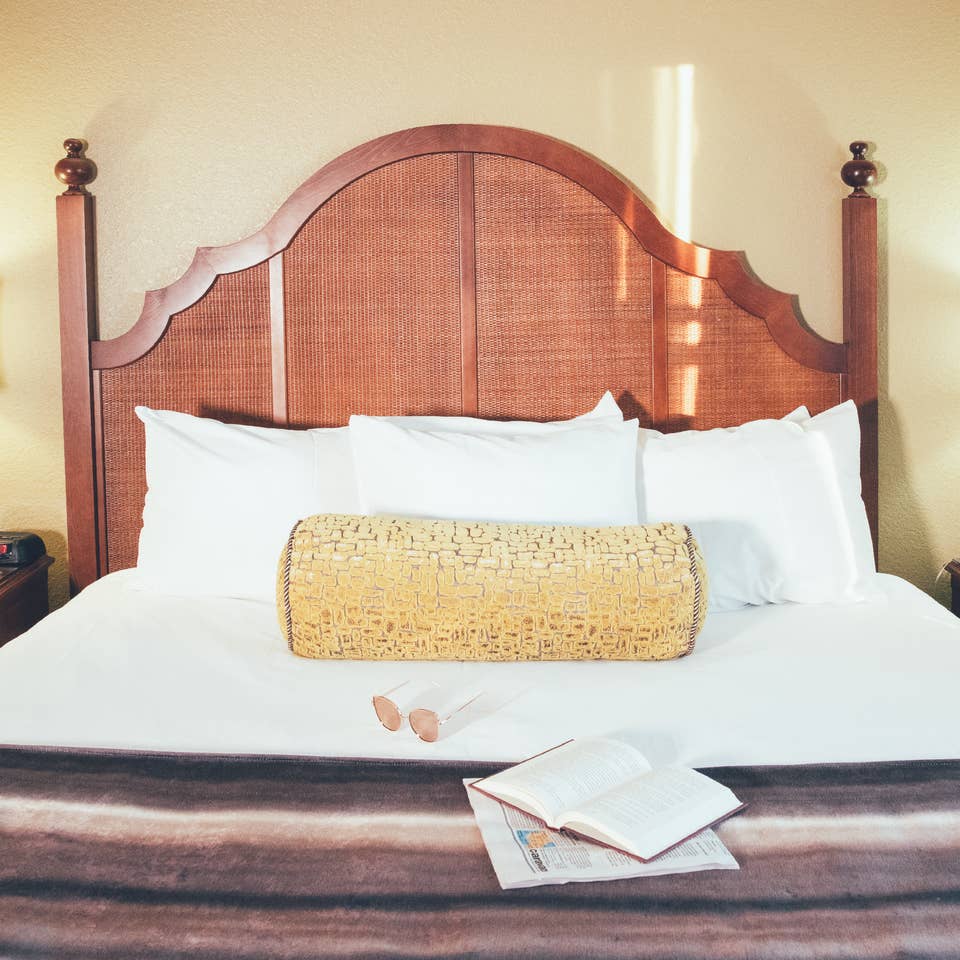 Bed with book and newspaper laying on top of covers in a Signature villa in River Island at Orange Lake Resort near Orlando, Florida