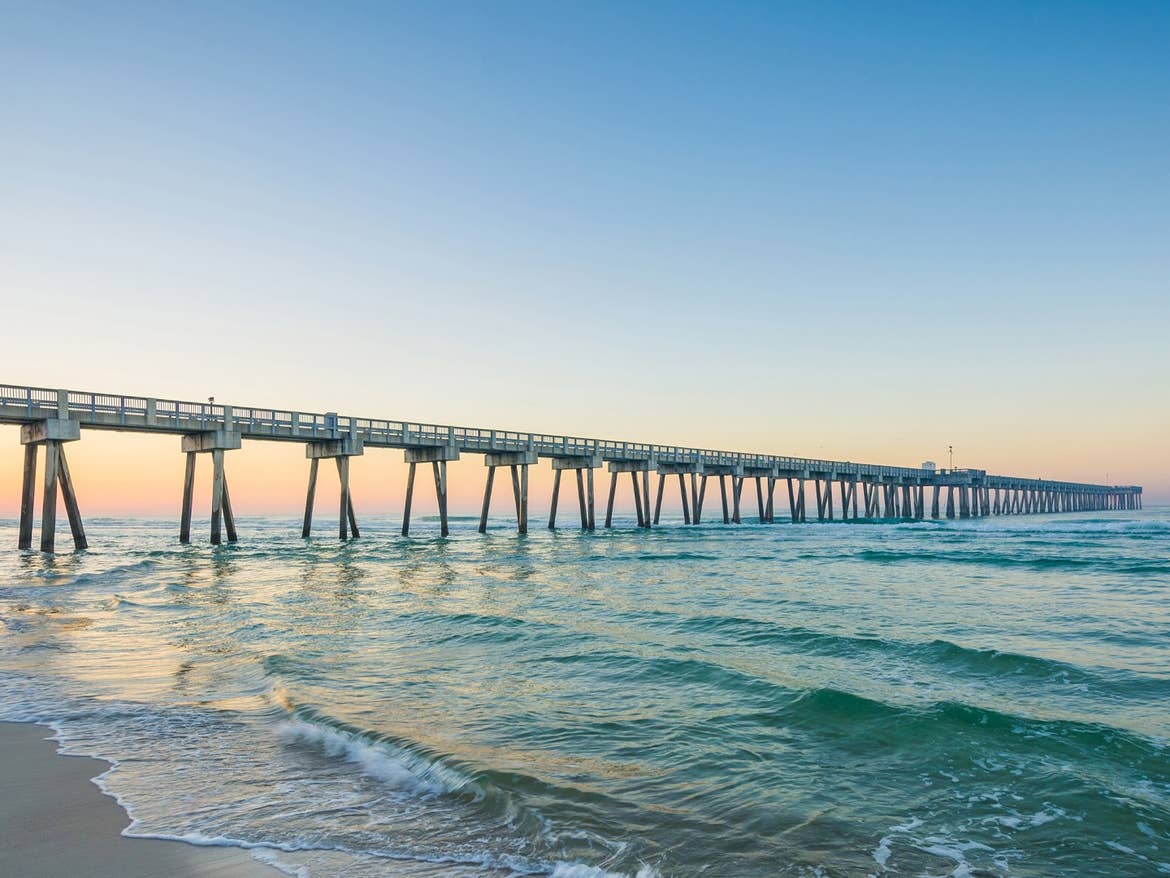 Sun sets behind a long pier on Panama City Beach.