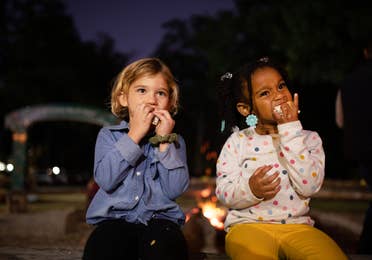 Two children eating s'mores outside during movie night at Falladays at Villages Resort.