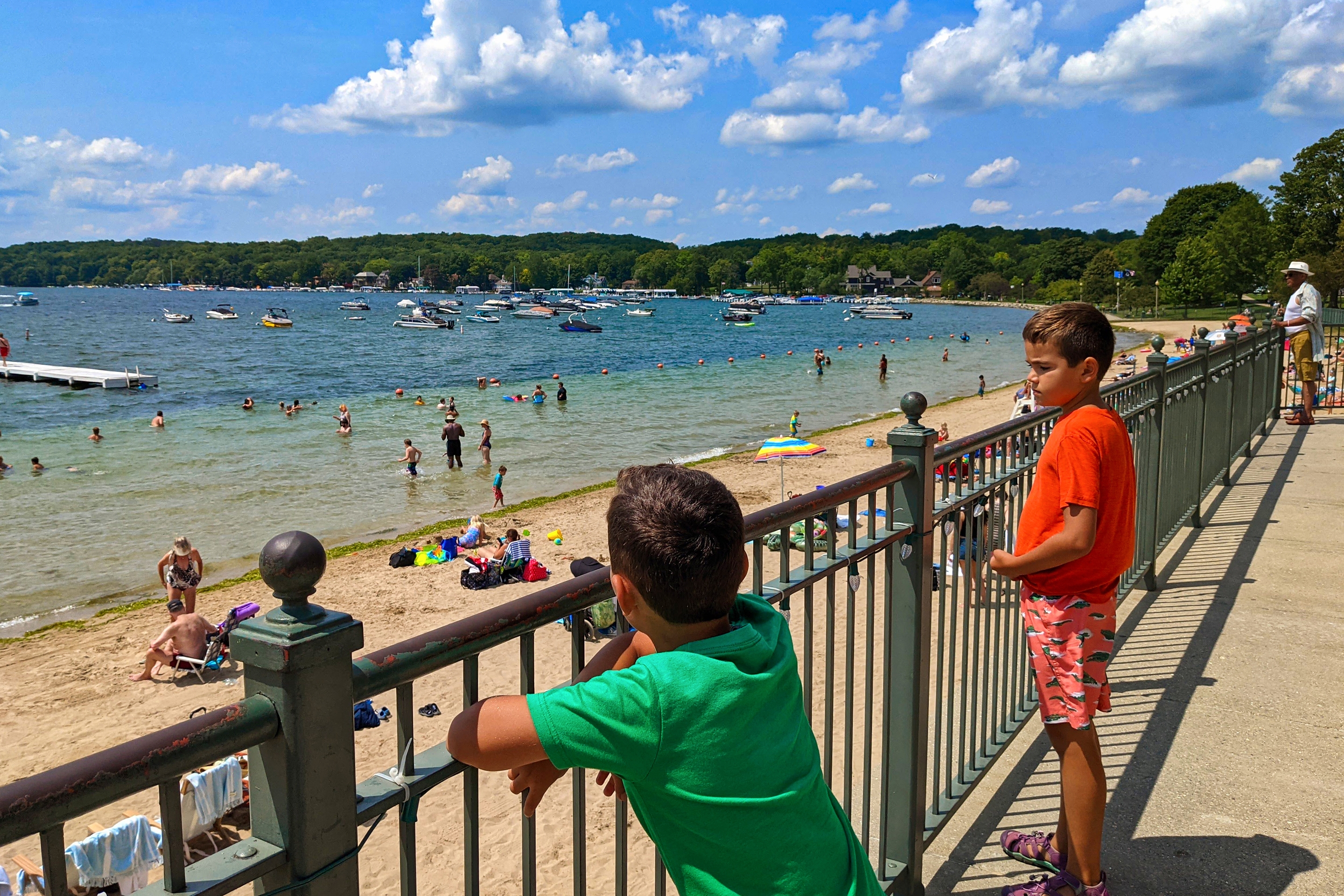 Two boys stand behind a rail overlooking the Beach of Lake Geneva.