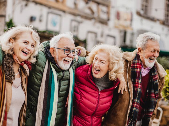 Four adults laughing together while wearing winter attire.