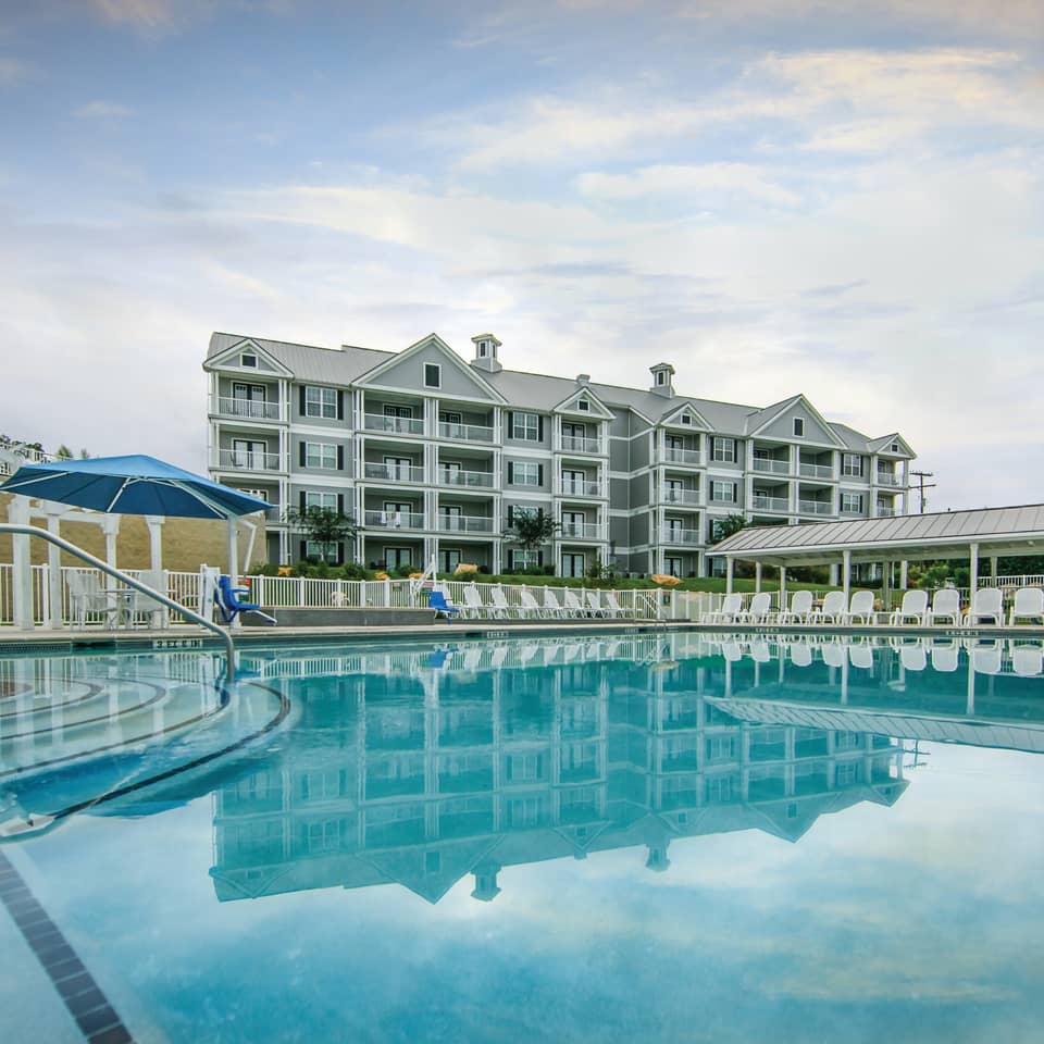 Outdoor pool and sun chairs with view of property building at Hill Country Resort in Canyon Lake, Texas