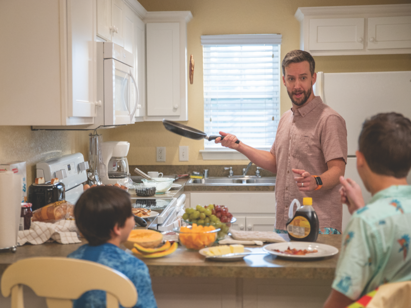 Dad cooking breakfast for kids in hotel kitchen.