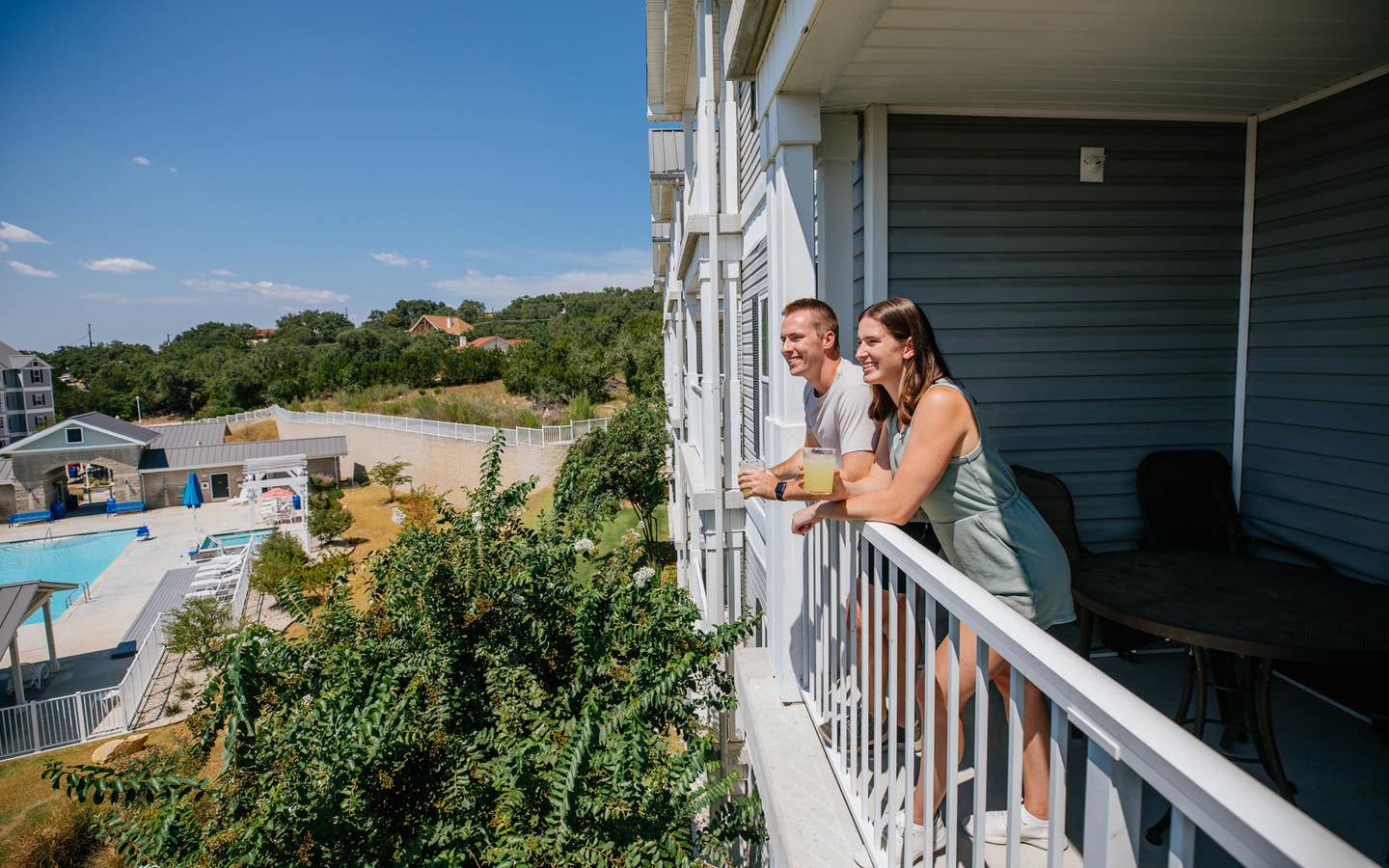 Two guests standing on balcony overlooking pool at Hill Country Resort at Canyon Lake in Texas.