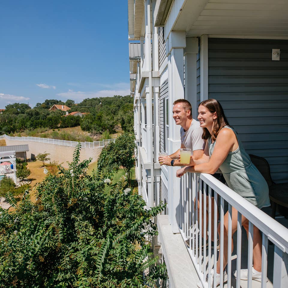 Two guests standing on balcony overlooking pool at Hill Country Resort at Canyon Lake in Texas.