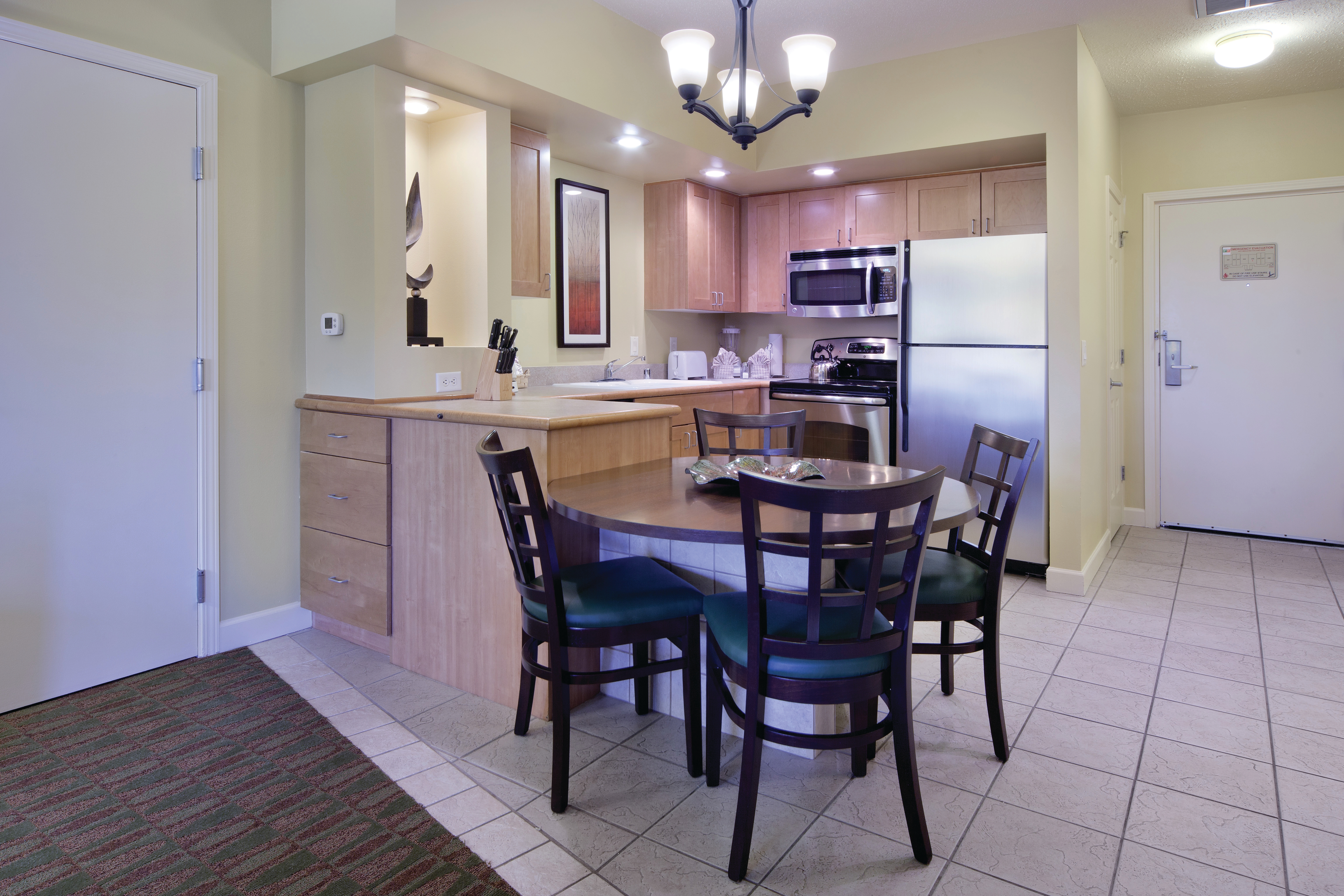 Dining room table with four chairs and view of kitchen in background in a one-bedroom villa at Lake Geneva Resort