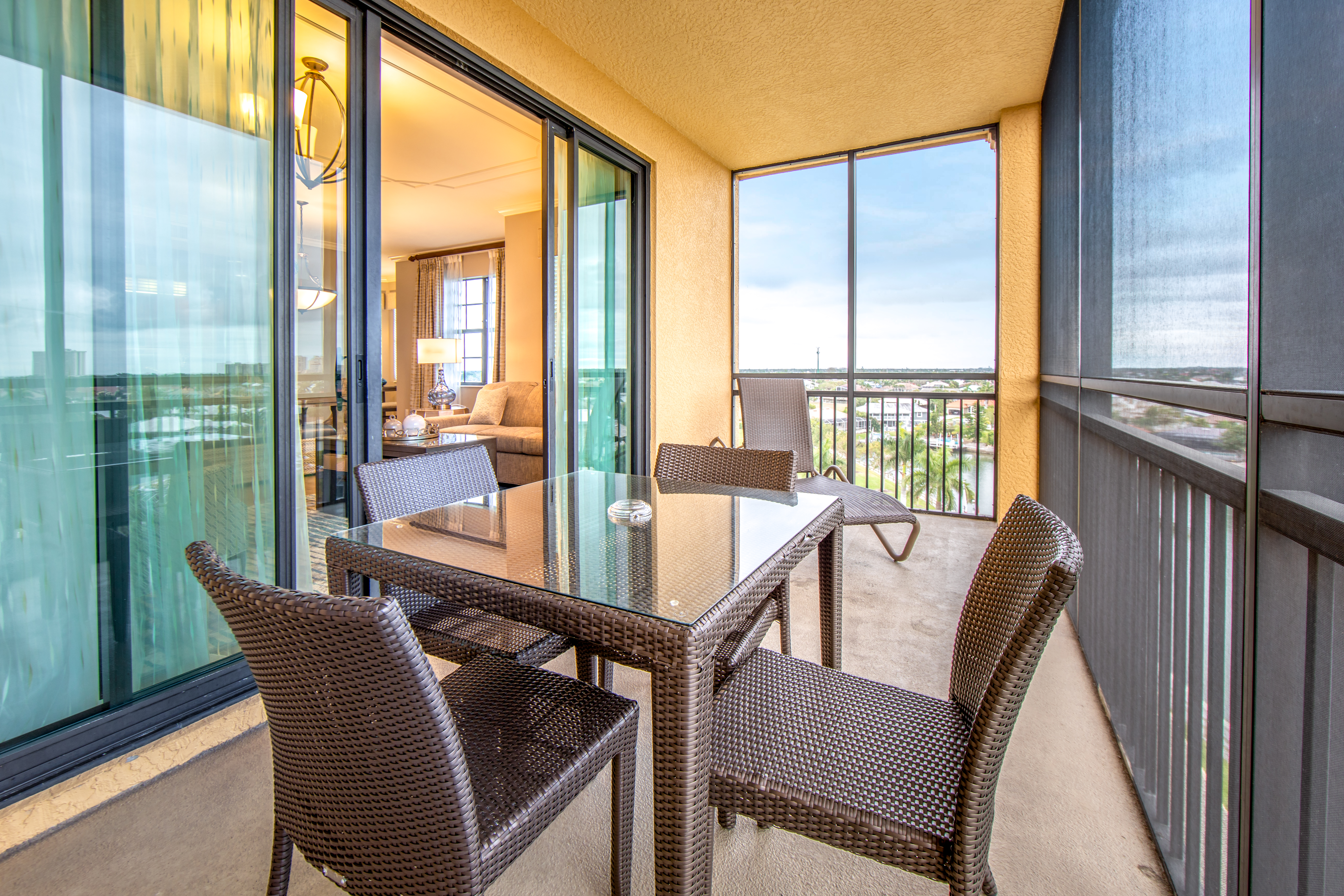 Furnished balcony with sun chair and small table with three chairs in a three-bedroom villa at Sunset Cove Resort in Marco Island, Florida