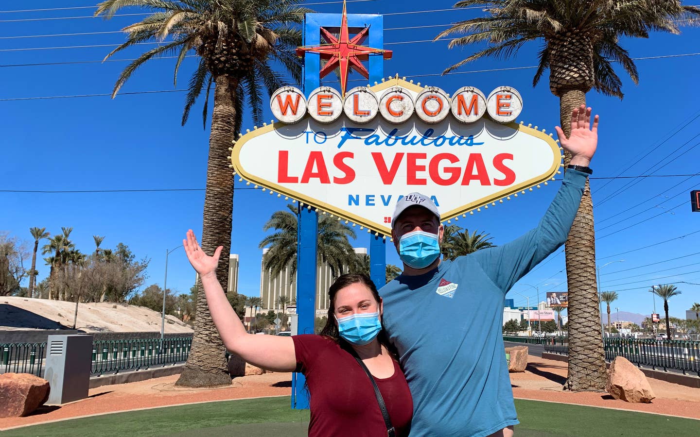 Featured Contributor, Ashley Fraboni (left) and her fiancé, Nicholas (right), pose in front of the 'Welcome to Las Vegas' marquee while wearing face masks.