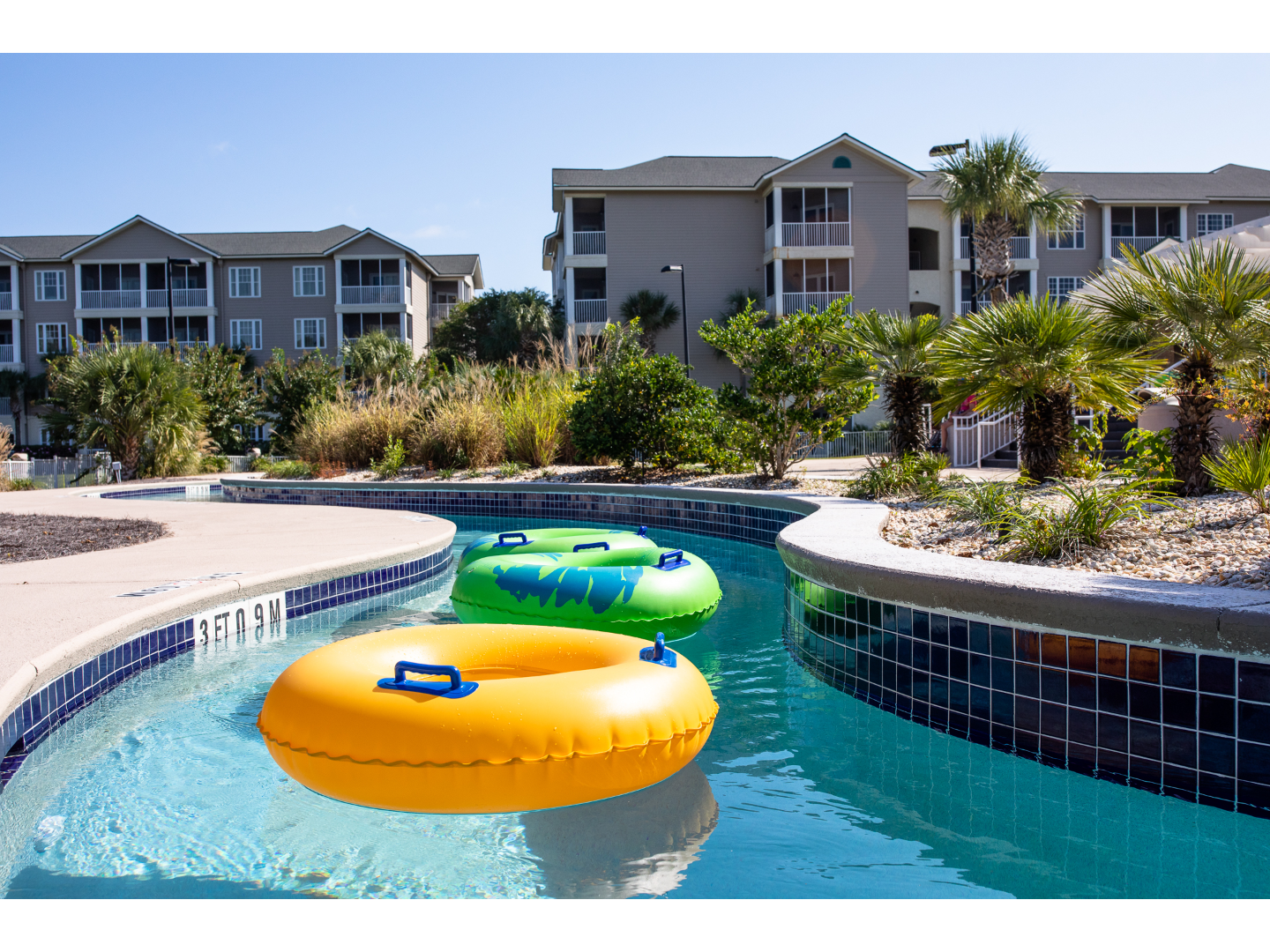 Colorful inflatable tubes floating along a resort lazy river.