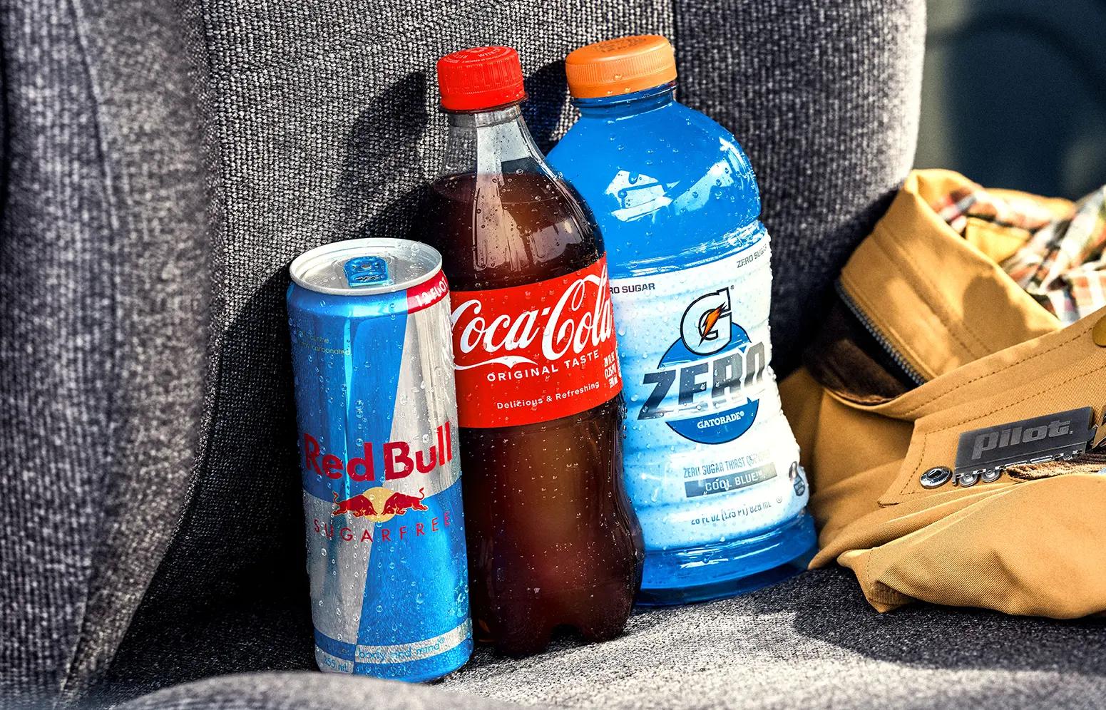 Three drinks lined up in the passenger seat: Red Bull, Coca-Cola, and Gatorade.