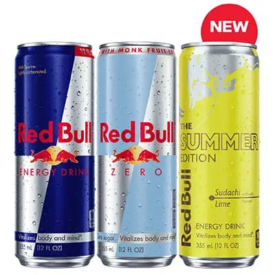 Three Red Bull energy drink cans standing side by side against a plain light background. From left to right: a classic blue and silver Red Bull can labeled “Energy Drink,” a light blue and silver “Red Bull Zero” can, and a bright yellow “The Summer Edition” can (Sudachi Lime flavor) with a red “NEW” badge above it; all cans have visible condensation droplets on the surface.