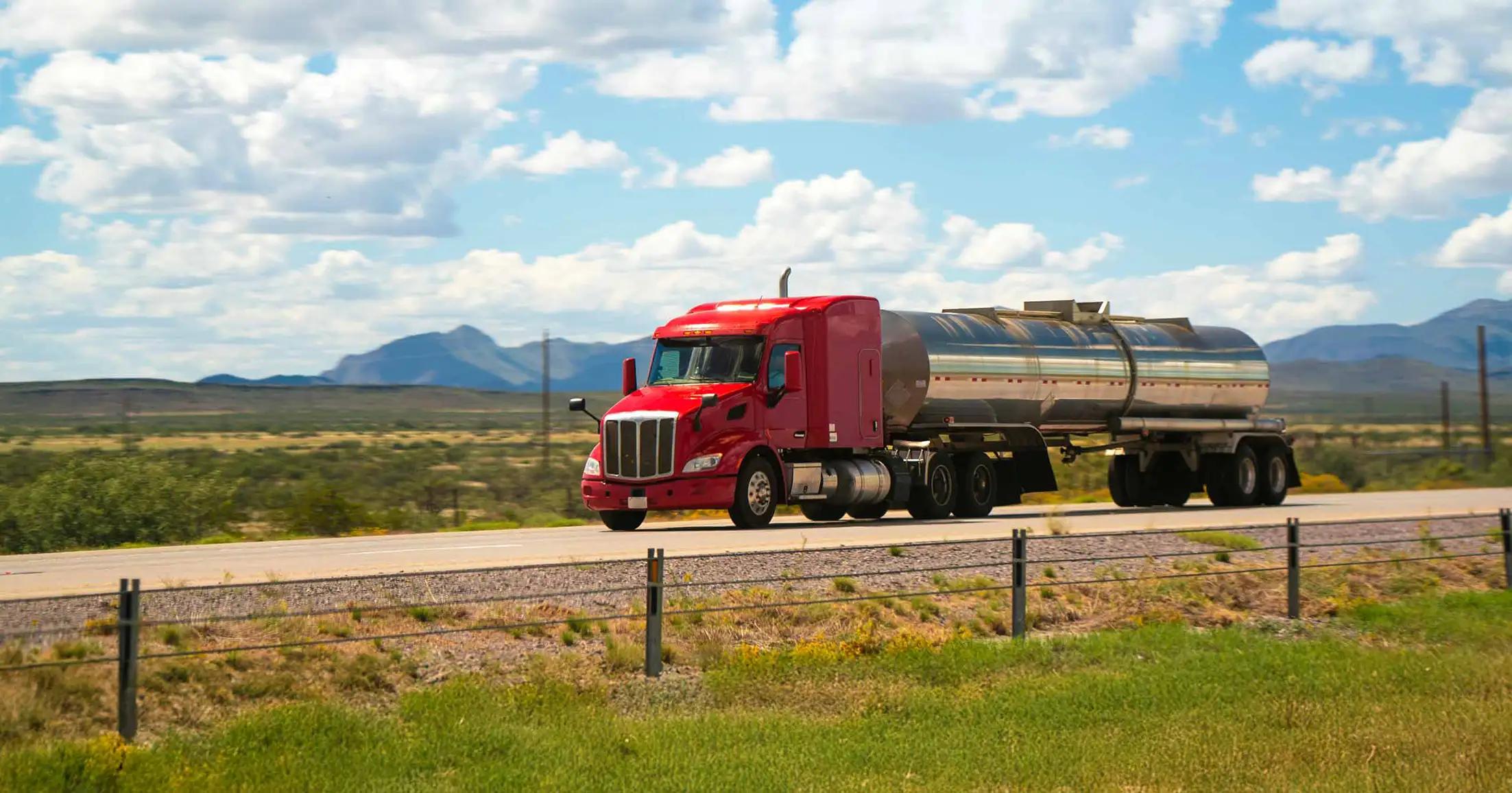 Fuel truck traveling down the road with mountains in the distance