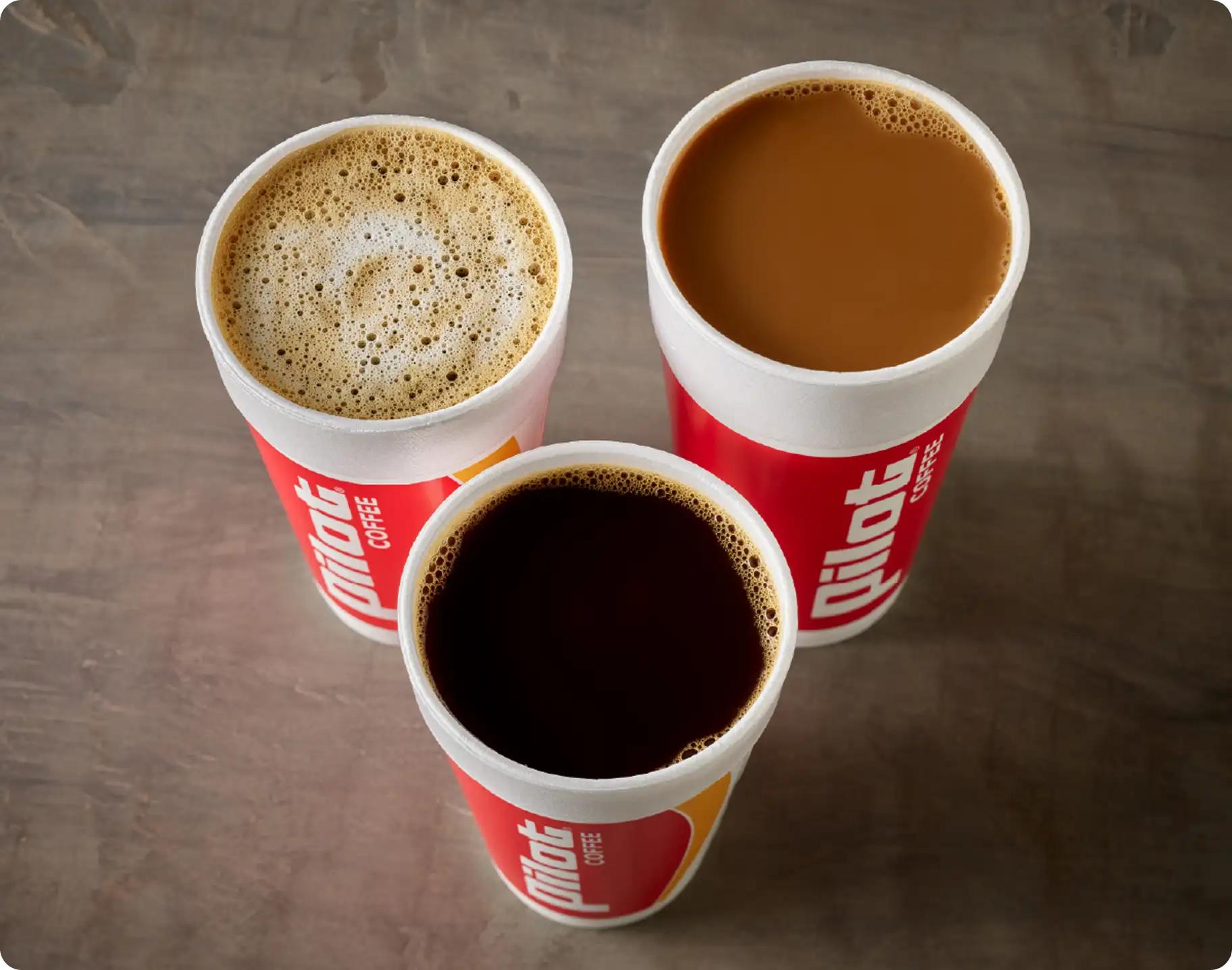 Three Pilot Coffee cups viewed from above showing different preparations: black coffee, coffee with cream or milk, and a frothy espresso-style coffee
