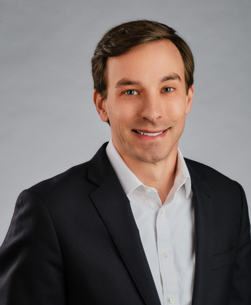 Jordan Spradling, smiling man wearing a dark blazer and white dress shirt, professional headshot